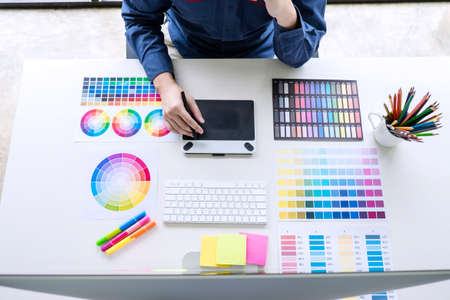 Image of male creative graphic designer working on color selection and drawing on graphics tablet at...