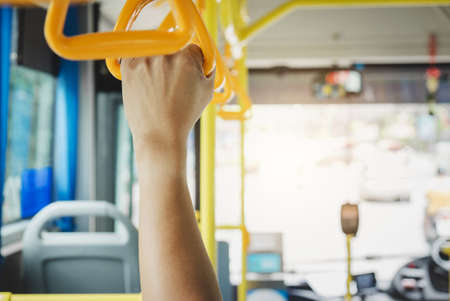 People Hand holding Handles for standing passenger in the city bus, transport, tourism and road trip concept.の写真素材