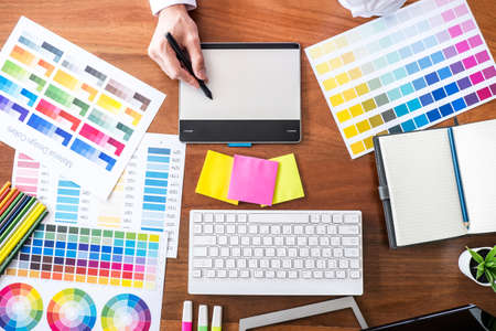 Image of male creative graphic designer working on color selection and drawing on graphics tablet at...