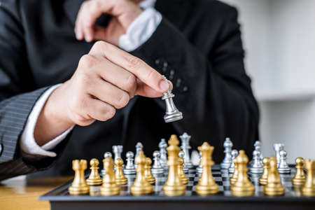 Hands of confident businessman playing chess game to development analysis new strategy plan, leader and teamwork concept for win and success.の写真素材