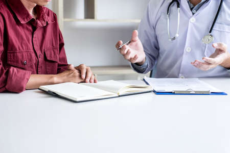 Doctor consulting patient discussing something and recommend treatment methods, presenting results on report, Medicine and health care concept.の写真素材