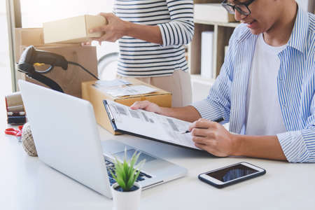 Small business owner delivery service and working packing box, business owner working checking order to confirm before sending customer in post office, Shipment Online Sales.の写真素材