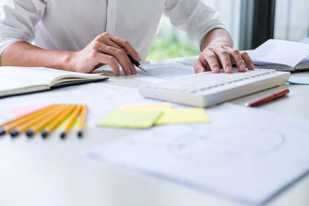 Businessman working writing business plan document and graphic designer with computer in office.