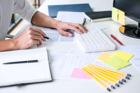 Businessman working writing making note business plan and graphic designer with computer in office.