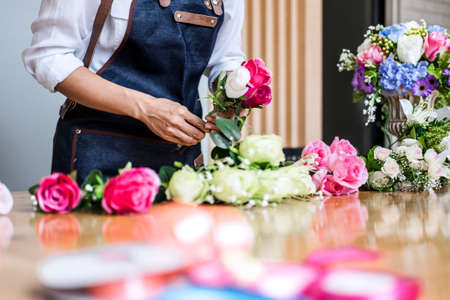 Arranging artificial flowers vest decoration at home, Young woman florist work making organizing diy artificial flower, craft and hand made concept.の写真素材