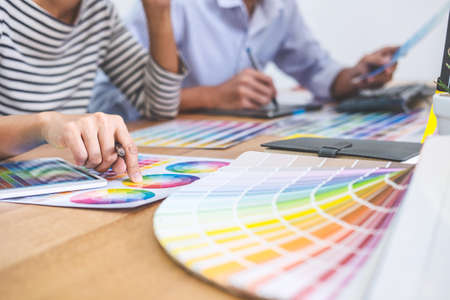 Two colleagues creative graphic designer working on color selection and drawing on graphics tablet...
