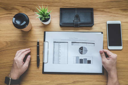 Businessman working on a graph document financial report and analysis calculation cost with...