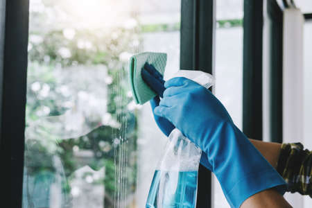 Husband housekeeping and cleaning concept, Happy young man wiping dust using a spray and a duster...