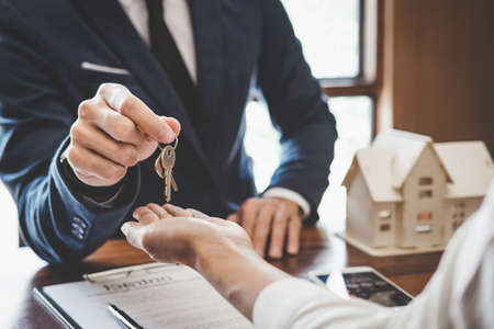 Real estate agent Sales manager holding filing keys to customer after signing rental lease contract of sale purchase agreement, concerning mortgage loan offer for and house insurance.の写真素材