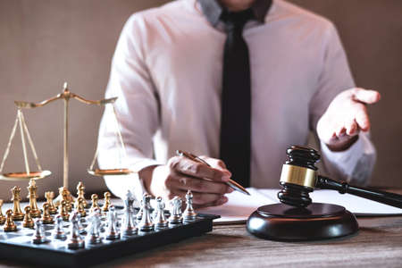 Legal law, advice and justice concept, Professional male lawyers working on courtroom sitting at the table and signing papers with gavel and Scales of justice.の写真素材
