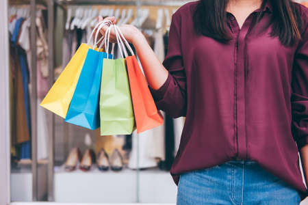 Consumerism, shopping lifestyle concept, Young woman standing and holding colorful shopping bags enjoying in shopping.の写真素材