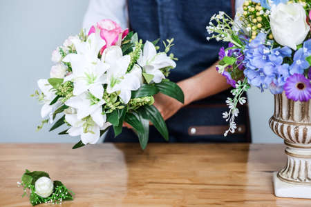 Arranging artificial flowers vest decoration at home, Young woman florist work making organizing diy artificial flower, craft and hand made concept.の写真素材