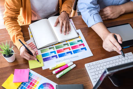 Two colleague creative graphic designer working on color selection and color swatches, drawing on...