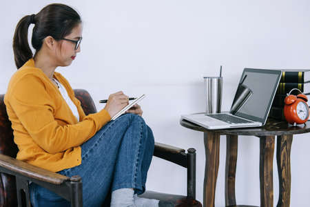 Happy casual young asian woman working in home or small office with using a laptop and document...