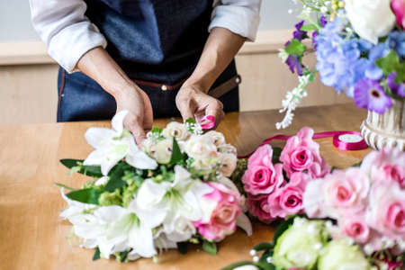 Arranging artificial flowers vest decoration at home, Young woman florist work making organizing diy artificial flower, craft and hand made concept.の写真素材