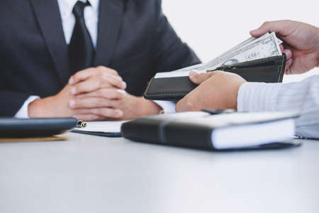 Bribery and corruption concept, bribe in the form of dollar bills, Businessman giving money while making deal to agreement a real estate contract and financial corporate.の写真素材