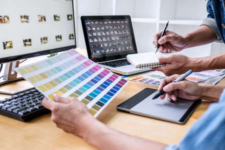 Two colleagues creative graphic designer working on color selection and drawing on graphics tablet at workplace, Color swatch samples chart for selection coloring.の写真素材