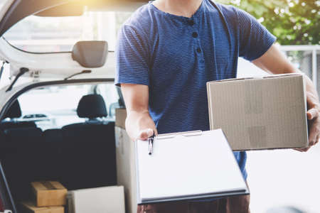 Home delivery service and working with service mind, deliveryman with boxes standing by in front of the customer house doors and holding clipboard.の写真素材