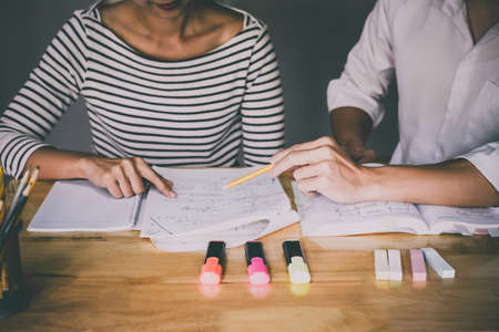 High school or college student group catching up workbook and learning tutoring in classroom and reading, doing homework and lesson practice preparing exam.の写真素材
