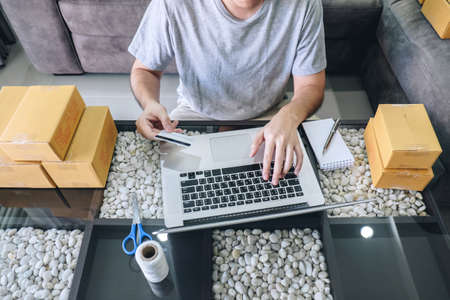 Small business parcel for shipment to client, Young man received online shopping parcel opening boxes and buying items by credit card, online marketing on purchase order package product.の写真素材