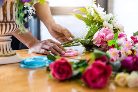 Arranging artificial flowers vest decoration at home, Young woman florist work making organizing diy artificial flower, craft and hand made concept.の写真素材