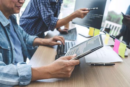 Two professional programmers cooperating at Developing programming and website working in a software develop company office, writing codes and typing data code.の写真素材