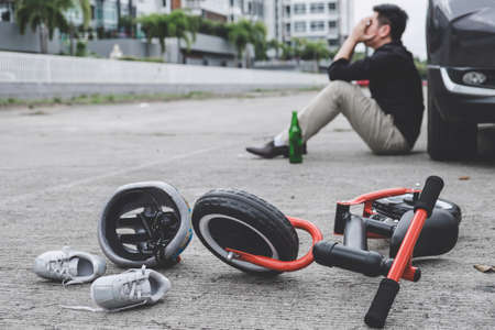 Image of shocked and scared driver after accident involved Kid's bike and helmet lying on the road on pedestrian crossing after accident collision with drunk car driver.の写真素材