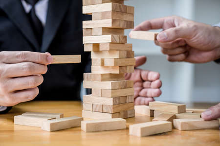 Images of hand of businesspeople placing and pulling wood block on the tower, Alternative risk concept, plan and strategy in business, Risk To Make Business Growth Concept With Wooden Blocks.の写真素材