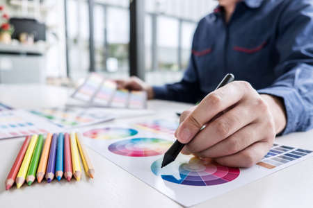 Image of male creative graphic designer working on color selection and drawing on graphics tablet at...