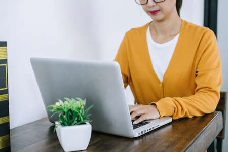 Happy casual young asian woman working in home or small office with using a laptop and document...