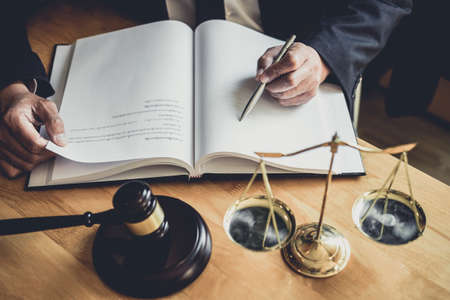 Male lawyer or judge working with contract papers, Law books and wooden gavel on table in courtroom,...