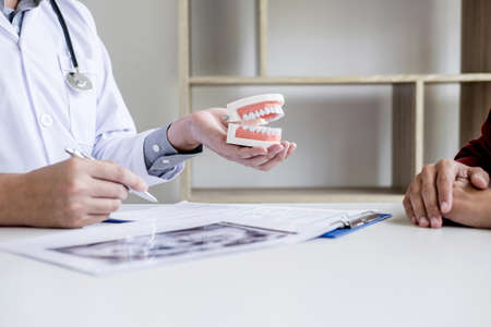 Male doctor or dentist writing report working with tooth x-ray film model and equipment used in the...