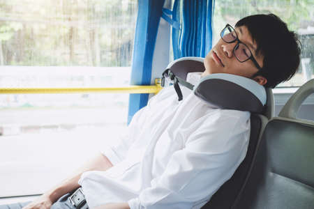 Young Asian man traveler sitting on a bus and sleeping with pillow, transport, tourism and road trip...