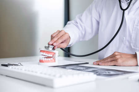 Male doctor or dentist checking teeth disease in dental model and equipment used in the treatment of...