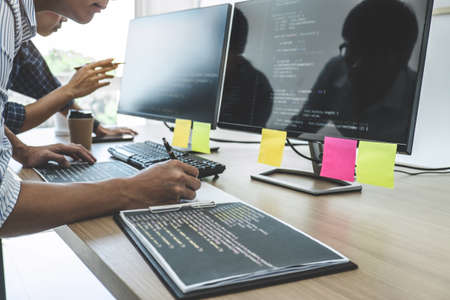 Two professional programmers cooperating at Developing programming and website working in a software develop company office, writing codes and typing data code.の写真素材