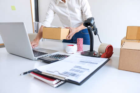 Young entrepreneur SME receive order client and working with packaging sort box delivery online market on purchase order and preparing package product, Small business parcel for shipment.の写真素材