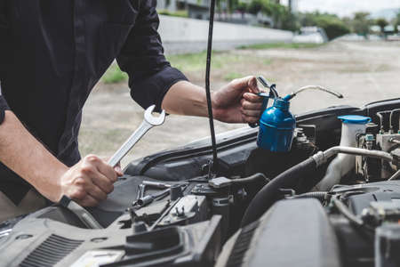 Services car engine machine concept, Automobile mechanic repairman hands repairing a car engine automotive workshop with a wrench and pouring oil, car service and maintenance.の写真素材