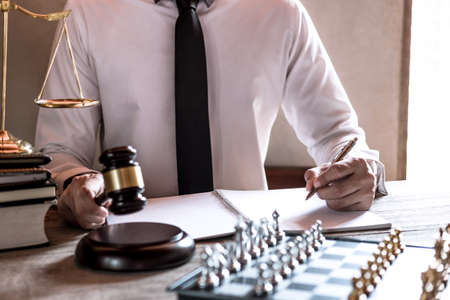 Legal law, advice and justice concept, Professional male lawyers working on courtroom sitting at the table and signing papers with gavel and Scales of justice.の写真素材