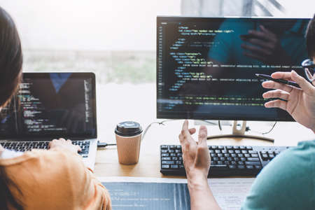 Writing codes and typing data code technology, Programmer cooperating working on web site project in a software developing on desktop computer at company, Programming with HTML, PHP and javascript.の写真素材