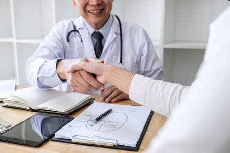 Professional Male doctor in white coat shaking hand with female patient after successful recommend treatment methods, Medicine and health care concept.の写真素材