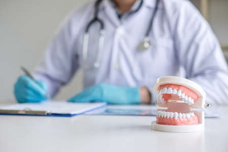 Male doctor or dentist working with patient tooth x-ray film, model and equipment used in the treatment and analysis teeth disease of dental and dentistry at workplace.の写真素材
