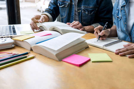 Education, teaching, learning, technology and people concept. Two high school students or classmates with helps friend do homeworks learning in classroom, Tutor books with friends.の写真素材