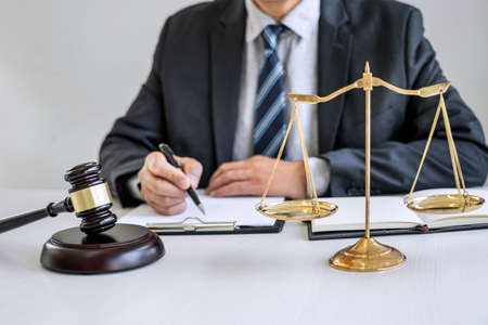 Male lawyer or judge working with contract papers, Law books and wooden gavel on table in courtroom, Justice lawyers at law firm, Law and Legal services concept.の写真素材