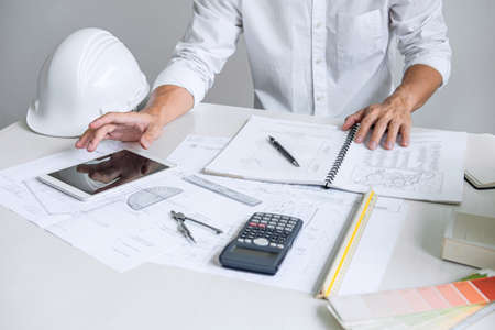 Architect working on blueprint, Engineer working with engineering tools for architectural project on workplace, Construction concept - building project, blueprints, ruler and dividers.の写真素材