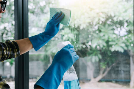 Husband housekeeping and cleaning concept, Happy young man wiping dust using a spray and a duster...