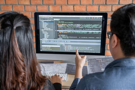 Programmers cooperating at Developing programming and website working in a software develop company office, writing codes and typing data code, Programming with HTML, PHP and javascript.の写真素材