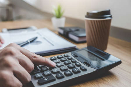 Businessman working on a graph document financial report and analysis calculation investment cost...
