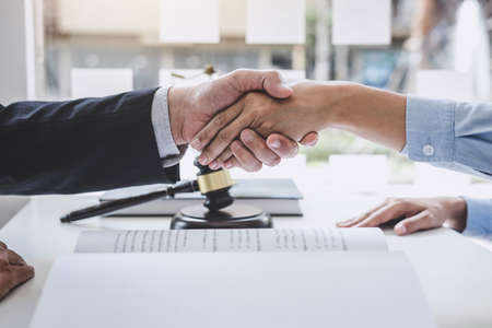 Handshake after good cooperation, Businesswoman Shaking hands with Professional male lawyer after discussing good deal of contract in courtroom, Concepts of law, Judge gavel with scales of justice.の写真素材