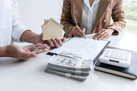Real estate agent Sales manager holding filing keys to customer after signing rental lease contract...