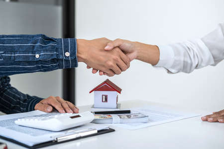Real estate agent and customers shaking hands together celebrating finished contract after signing about home insurance and investment loan, handshake and successful deal.の写真素材